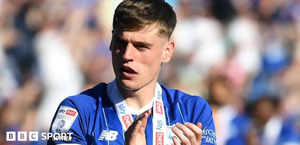Player in blue jersey applauding fans after match