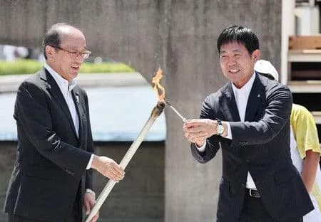 Two officials exchanging a lit torch ceremony