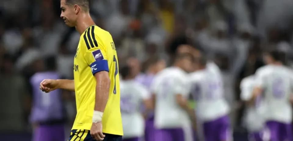 Player in yellow kit walking past celebrating teammates