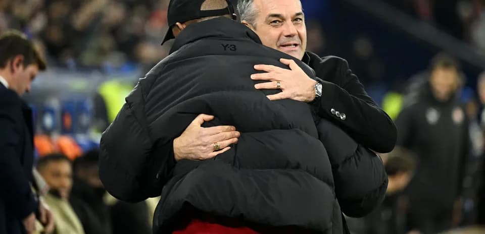 Two coaches embracing on the sidelines during match