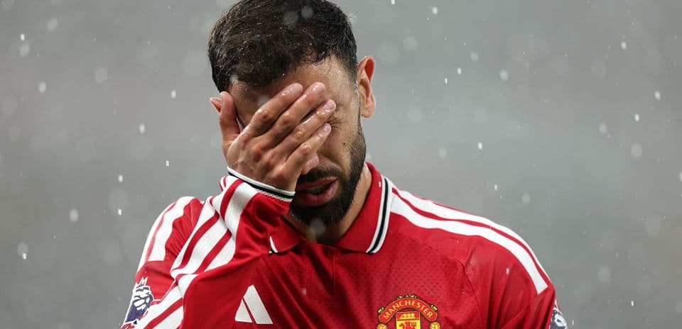 Player in Manchester United kit covering face with hand