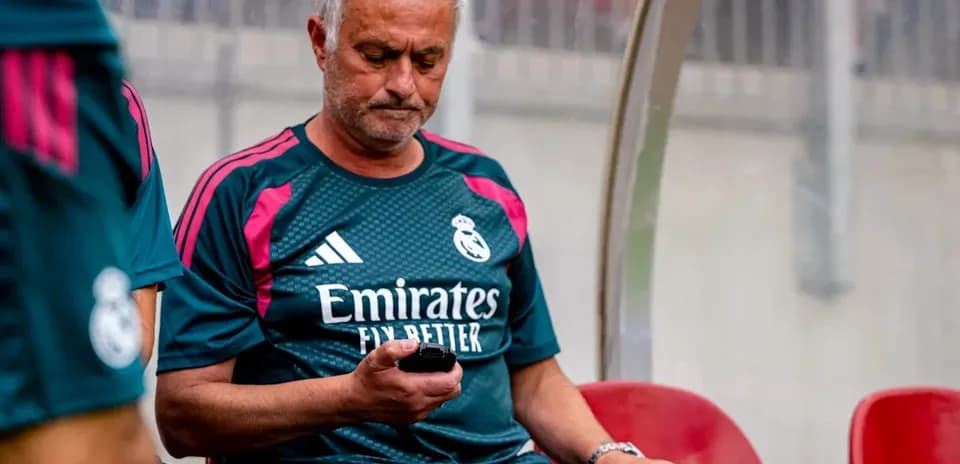 Coach seated on bench looking at mobile phone