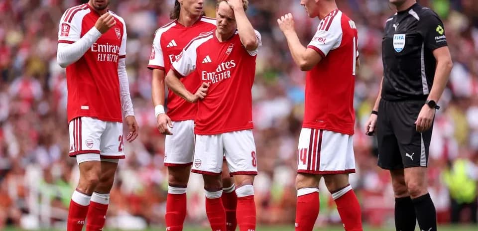 Arsenal players discussing a play with referee