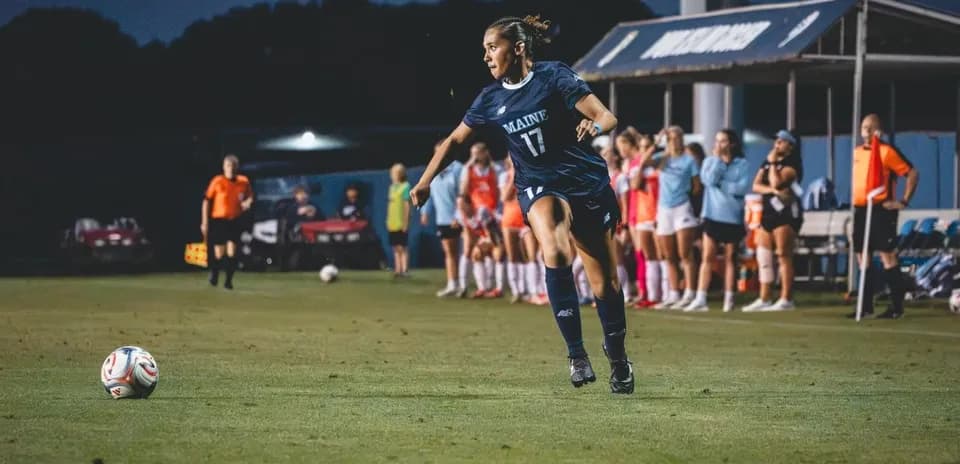 Player from Maine taking a corner kick on field