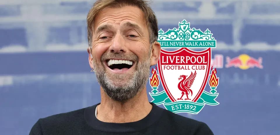 Manager smiling at press conference with Liverpool logo