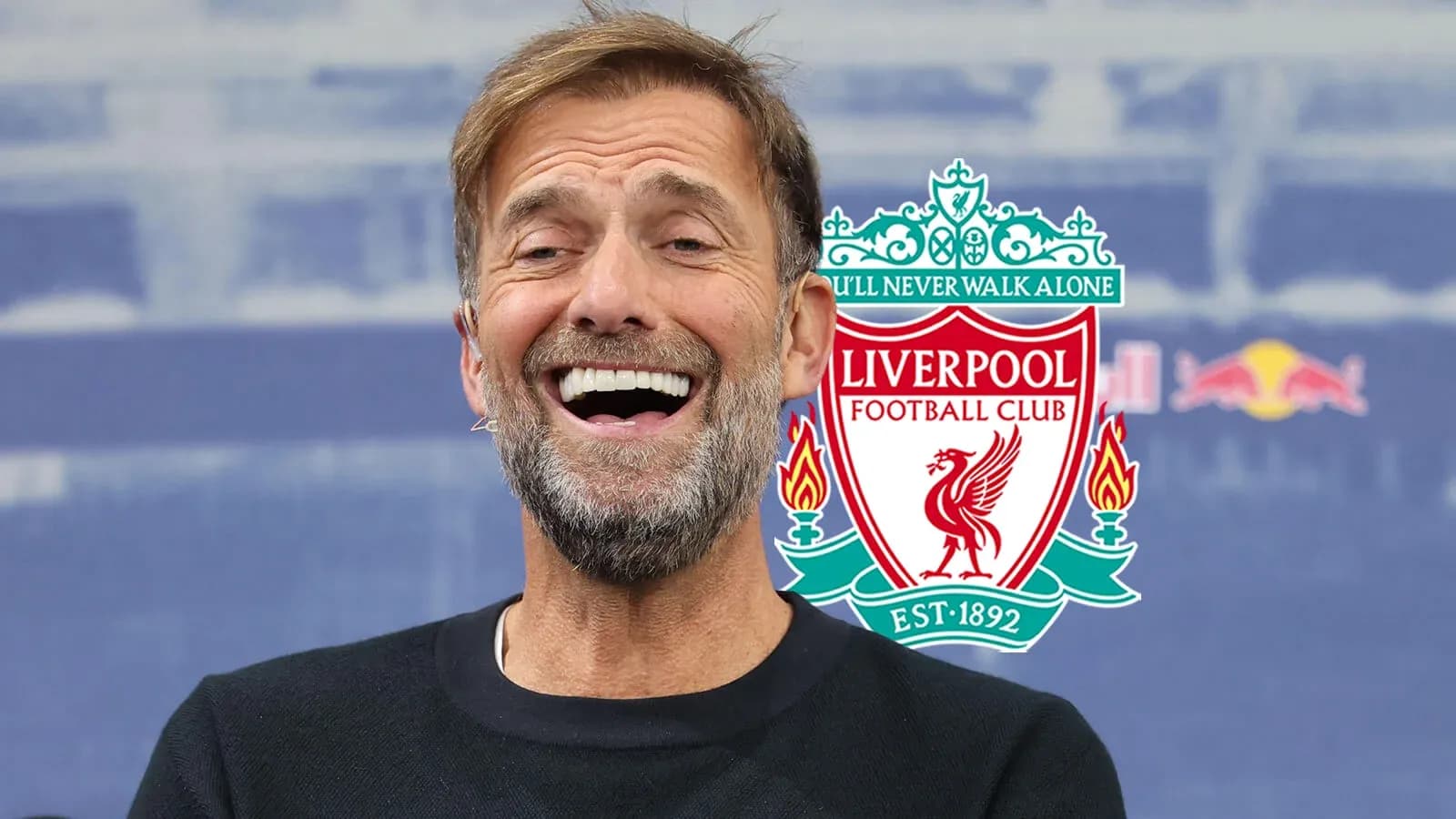 Manager smiling at press conference with Liverpool logo
