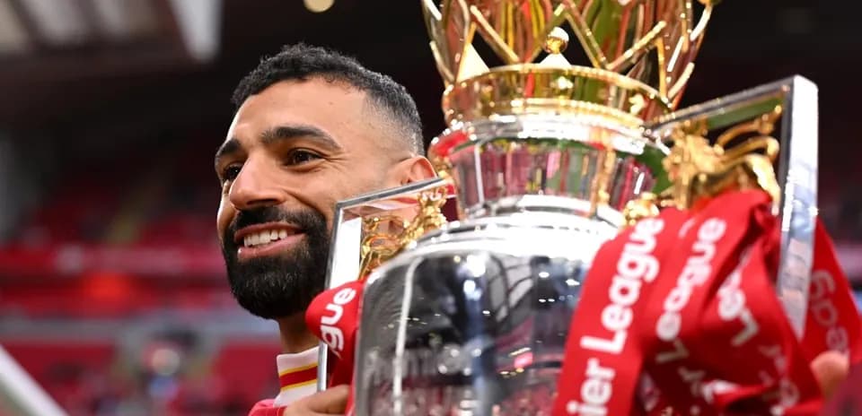 Player holding Premier League trophy in celebration