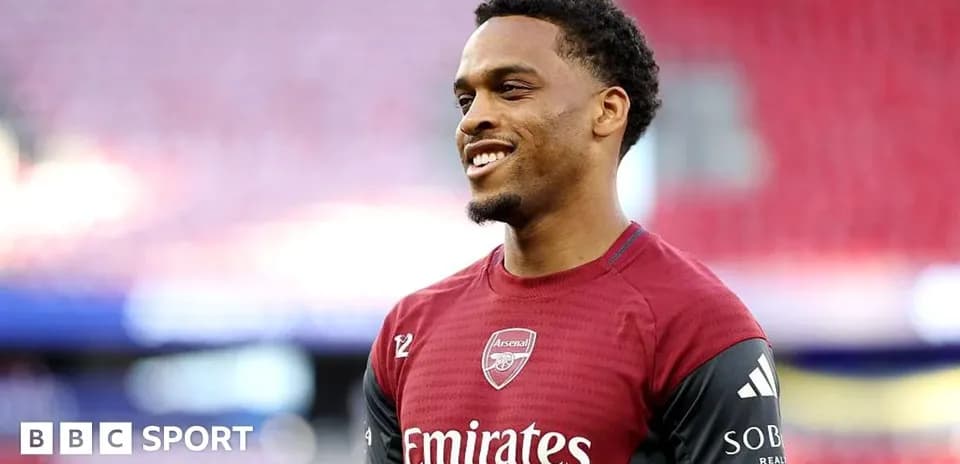 Player smiling in Arsenal training kit on pitch