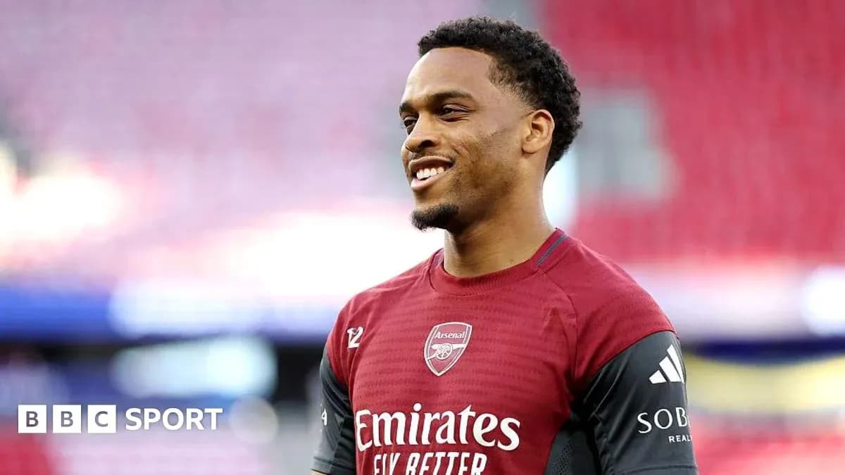 Player smiling in Arsenal training kit on pitch