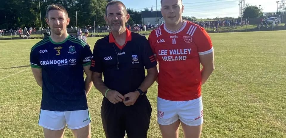 Two players and referee posing on the pitch