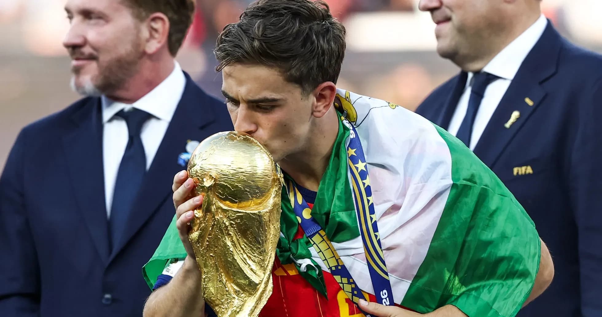 Player kissing World Cup trophy, wearing national flag