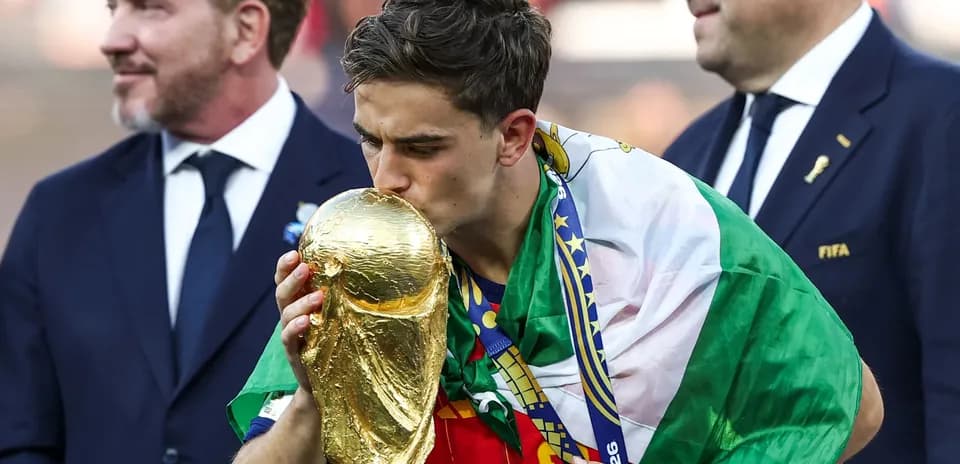 Player kissing World Cup trophy, wearing national flag