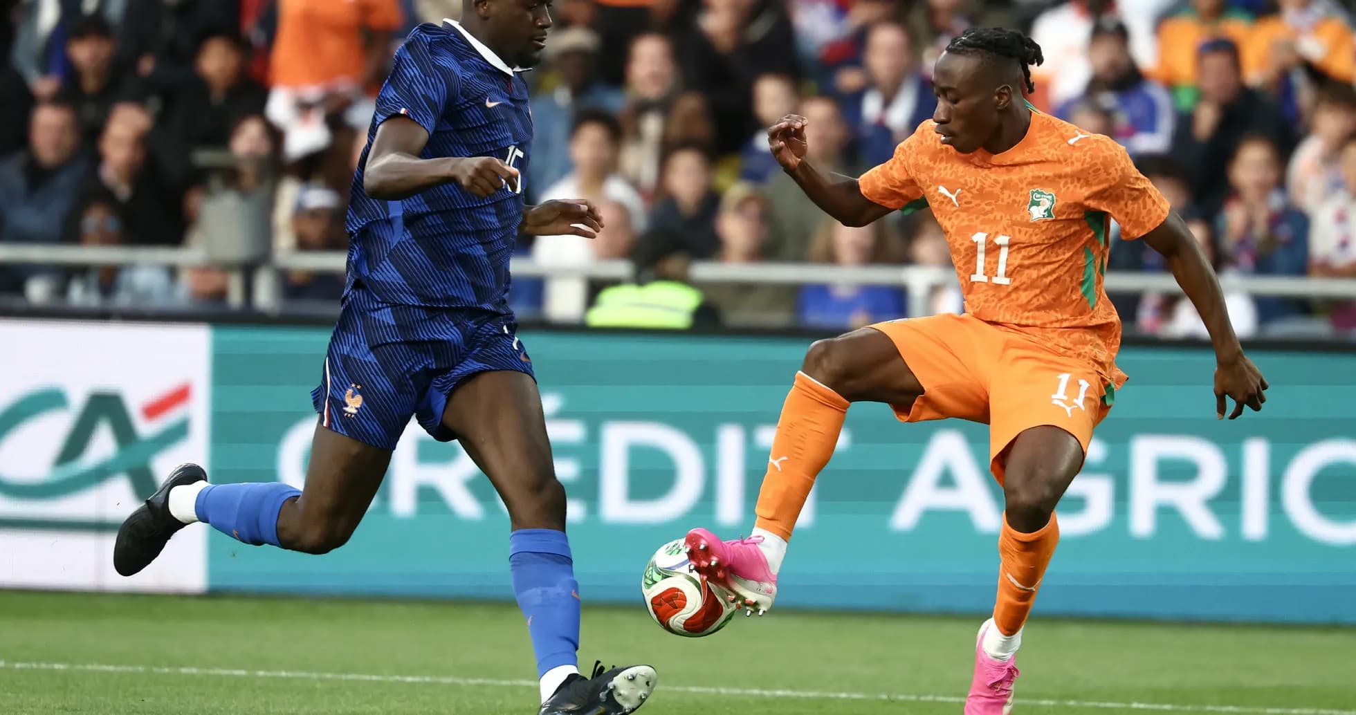 Player in orange dribbling past defender in blue