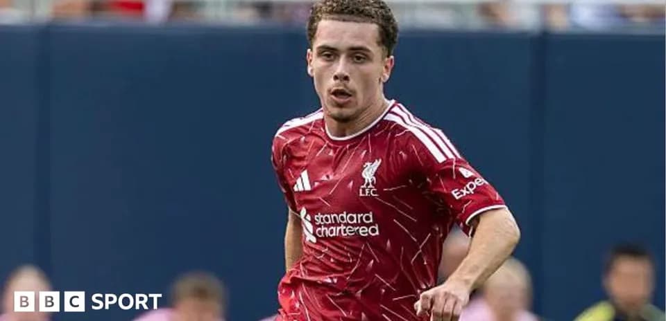 Player running on field wearing Liverpool jersey