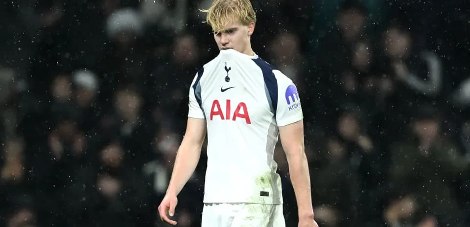 Player in Tottenham kit walking on a rainy pitch