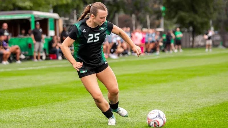Player 25 kicking the soccer ball on field