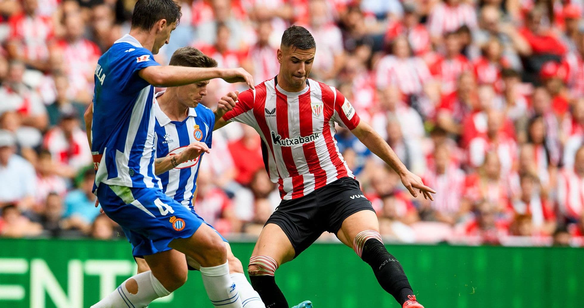 Espanyol player challenging Athletic Club opponent