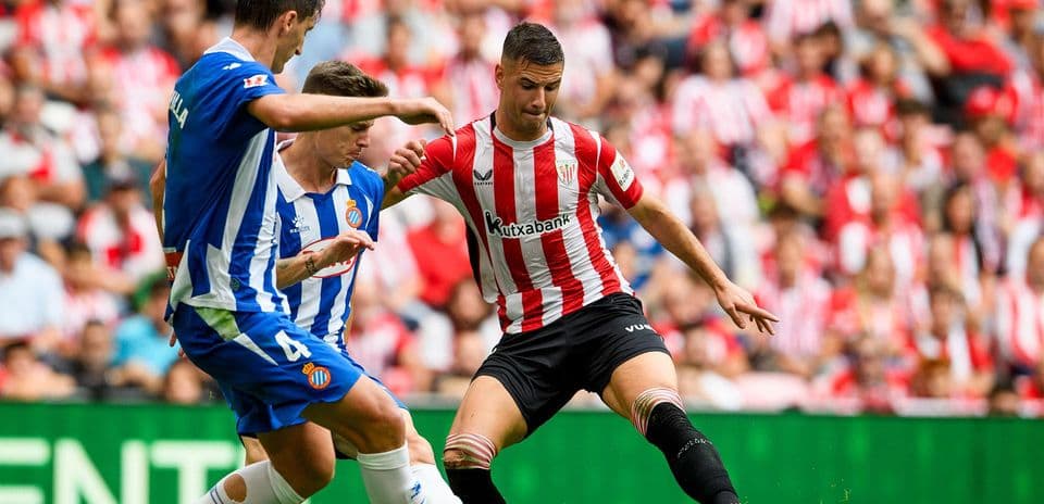 Espanyol player challenging Athletic Club opponent