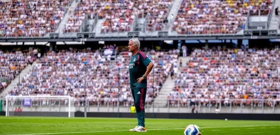 Coach observing match from sidelines in crowded stadium