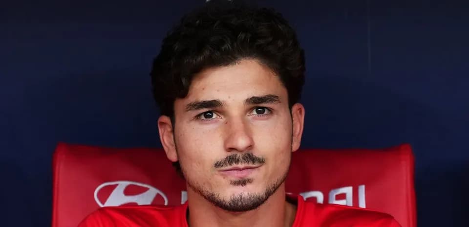 Player seated on bench in red team jersey