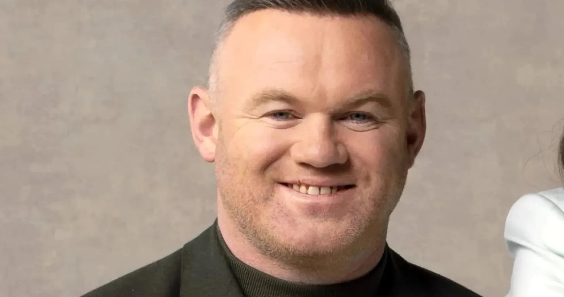 Smiling man in a dark jacket against neutral background