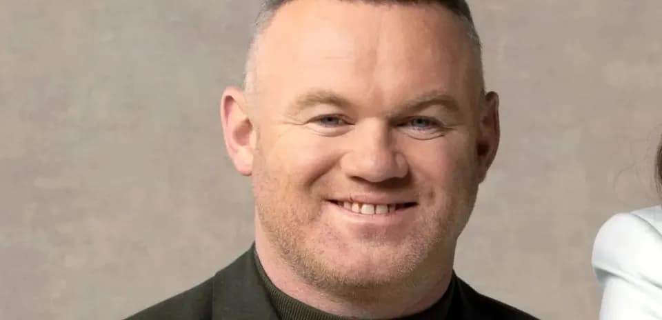 Smiling man in a dark jacket against neutral background