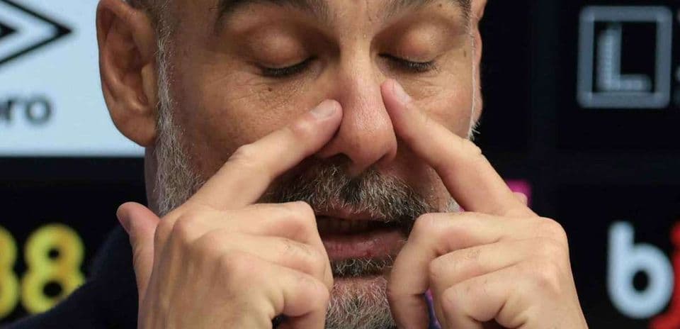 Coach gesturing during press conference with closed eyes