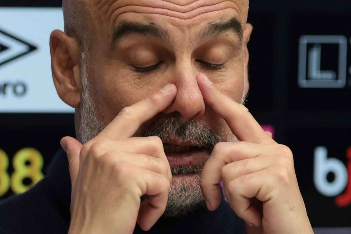 Coach gesturing during press conference with closed eyes