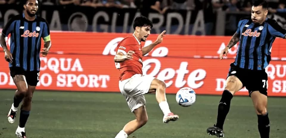 Player kicking ball during match with opposing players nearby