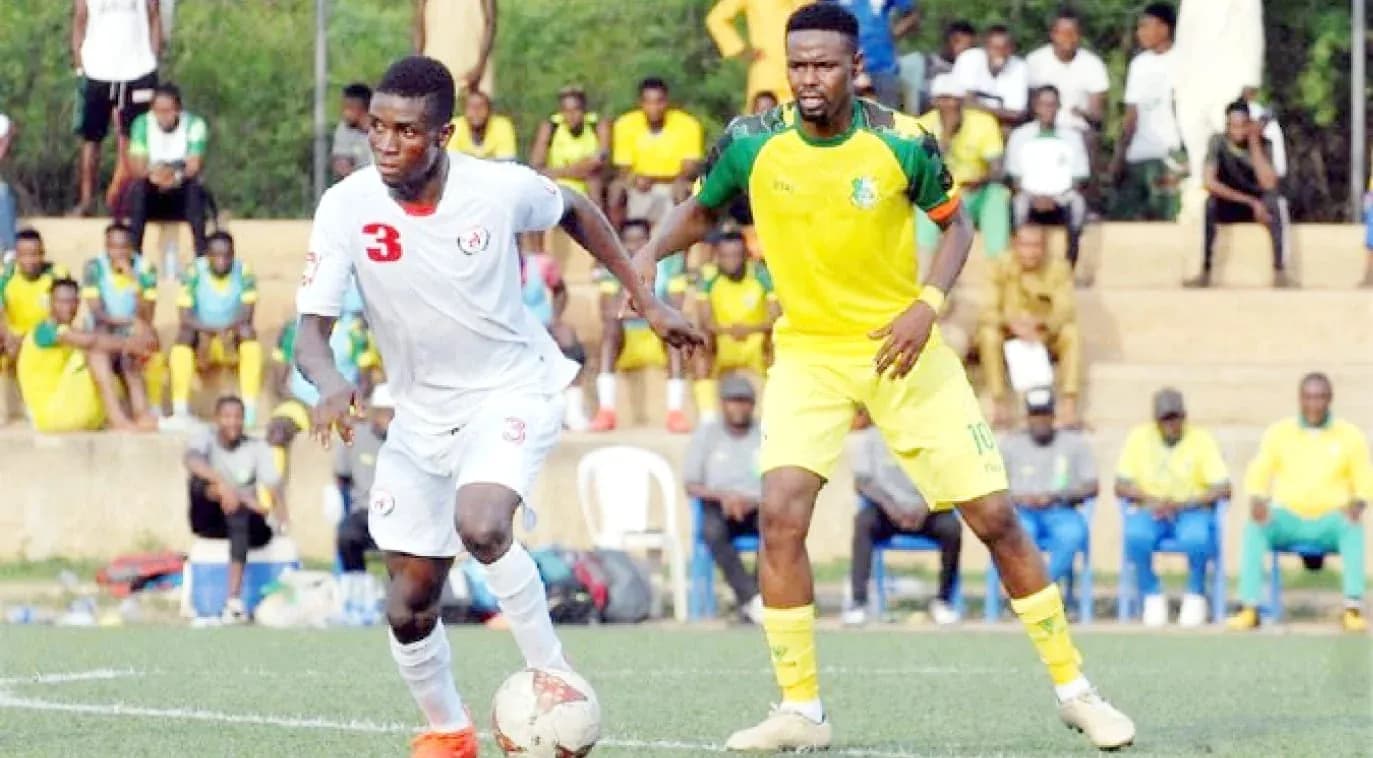 Warri Wolves player dribbling past Enugu Rangers defender