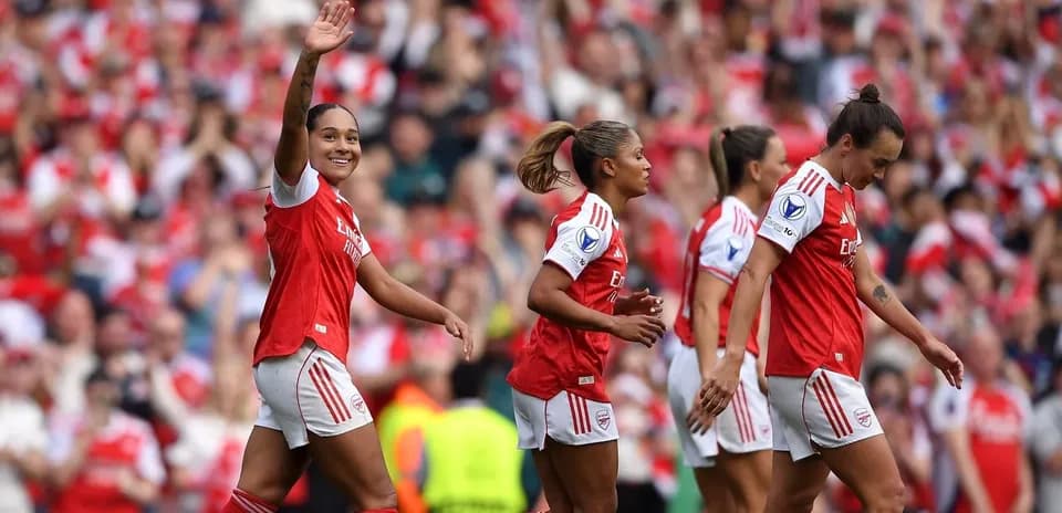 Arsenal players celebrating a goal with fans in background