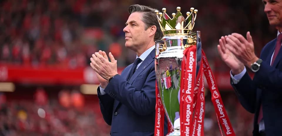 Man applauding next to Premier League trophy presentation