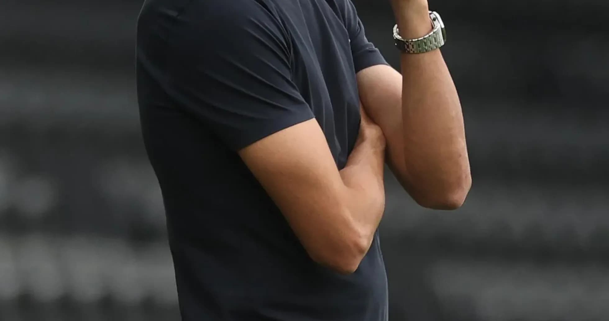 Coach observing match with arms crossed