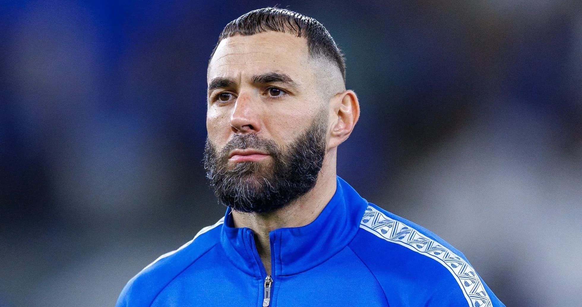 Football player in blue training jacket looking focused