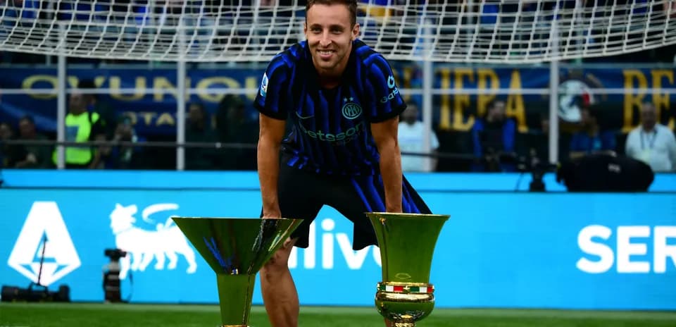 Player celebrating with two trophies on field