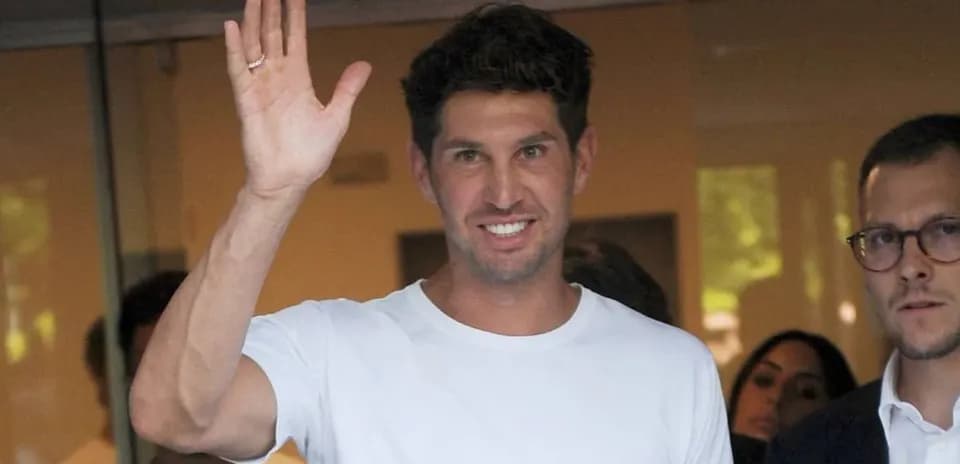 Man waving while wearing a white shirt