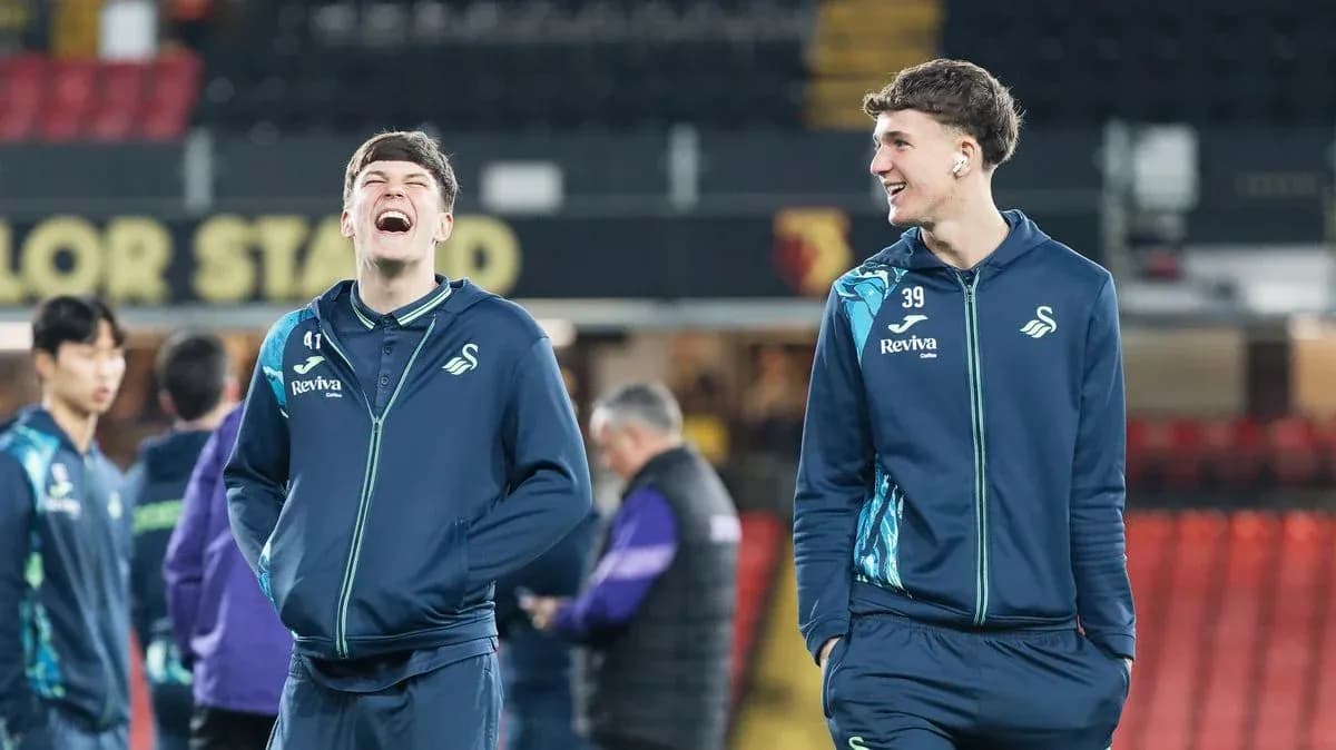 Two Swansea City players smiling during warm-up