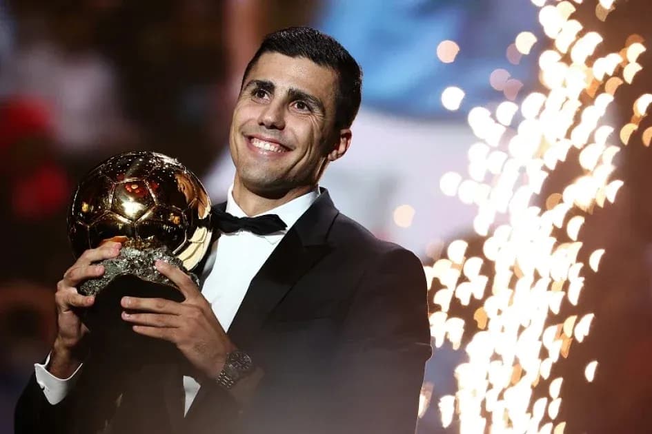 Player celebrating with Ballon d'Or trophy on stage