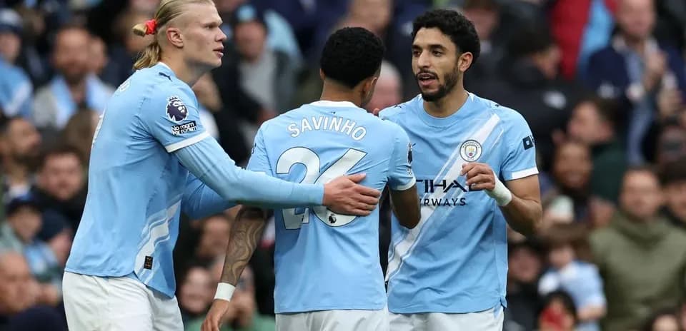 Three Manchester City players discussing on the pitch