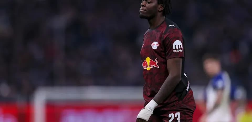 Goalkeeper in red kit walking on the pitch