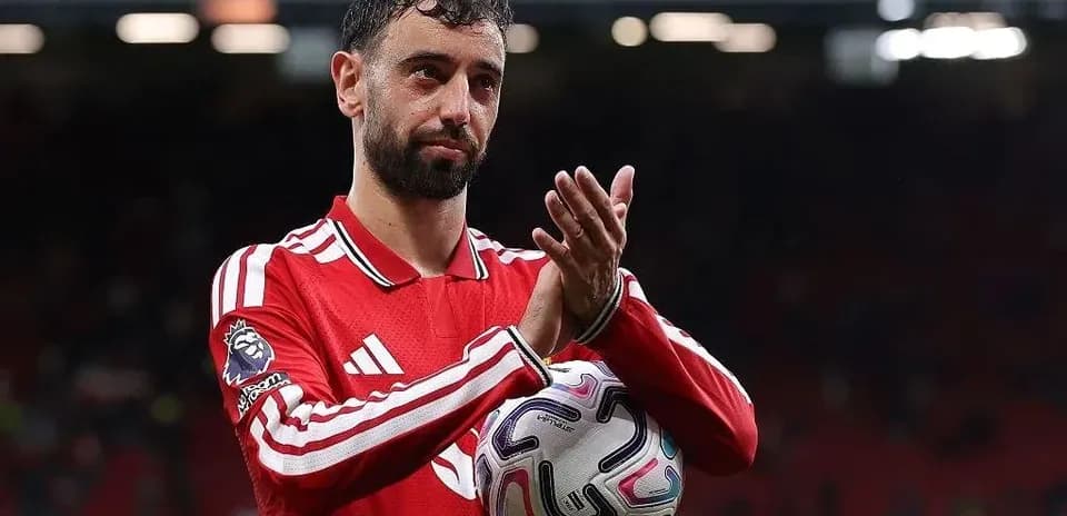 Player applauding fans while holding a football