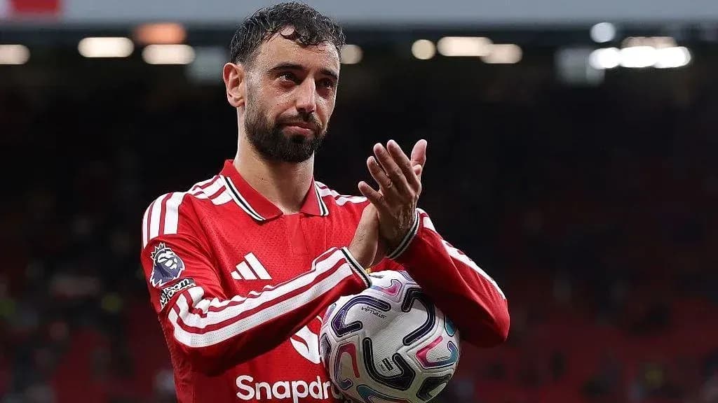 Player applauding fans while holding a football
