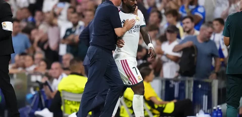 Coach assisting player Vinícius Júnior off the field