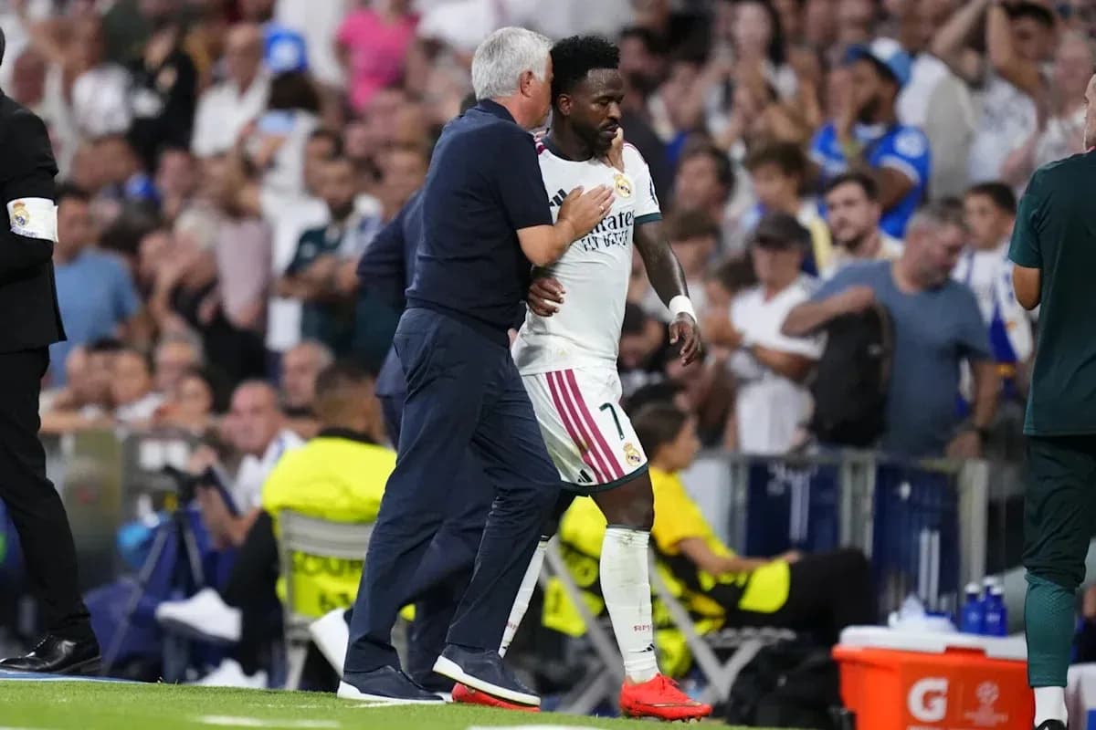 Coach assisting player Vinícius Júnior off the field