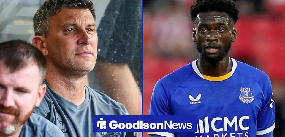 Coach observing match alongside player in Everton jersey