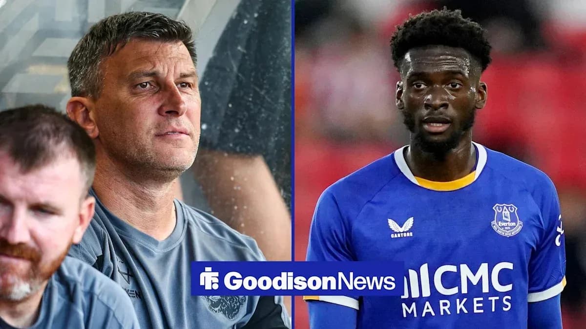 Coach observing match alongside player in Everton jersey