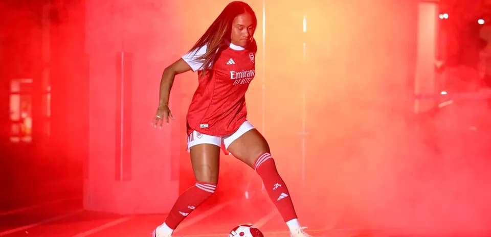 Player in Arsenal kit kicking a soccer ball