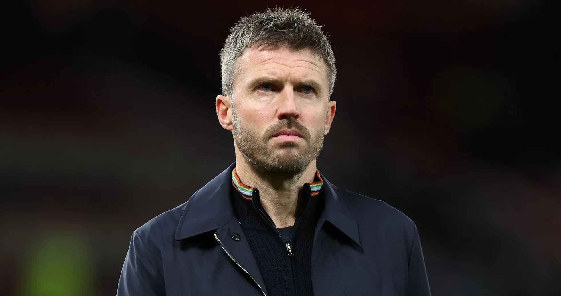 Man in dark jacket looking serious on field