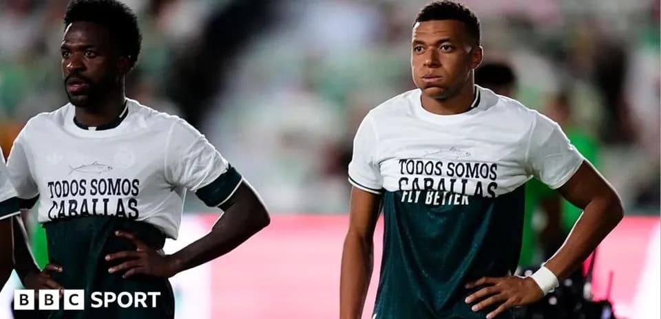 Two players wearing warm-up shirts on pitch