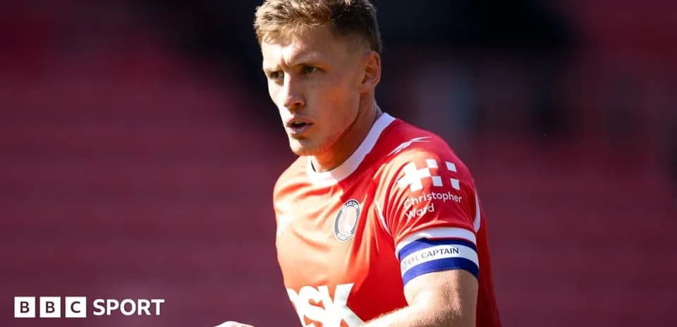 Player in red kit with captain's armband on pitch